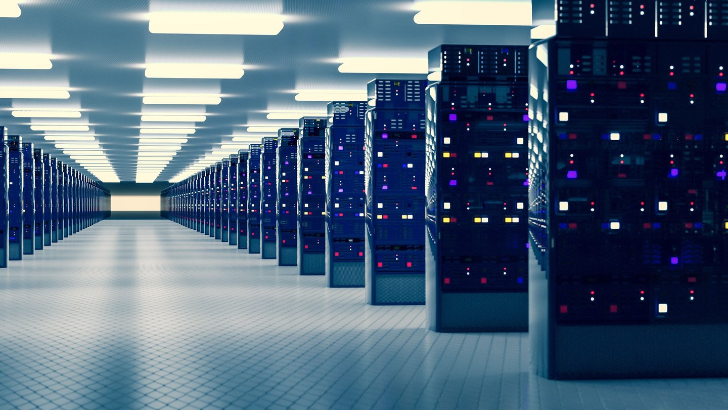 Rows of illuminated server racks line an aisle in a data center.