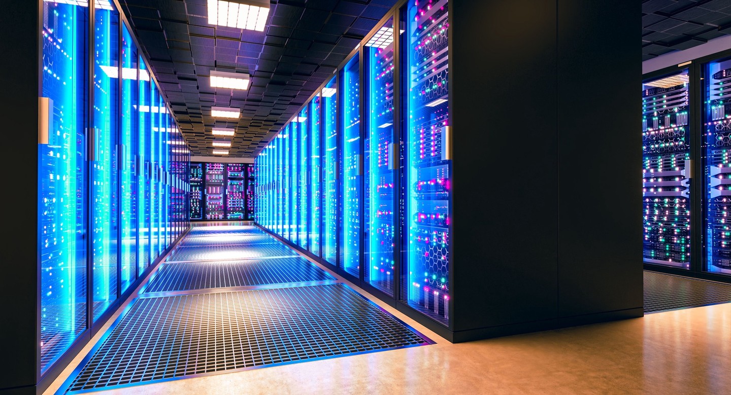 Blue-lit server racks line a modern data center corridor with reflective glass panels.