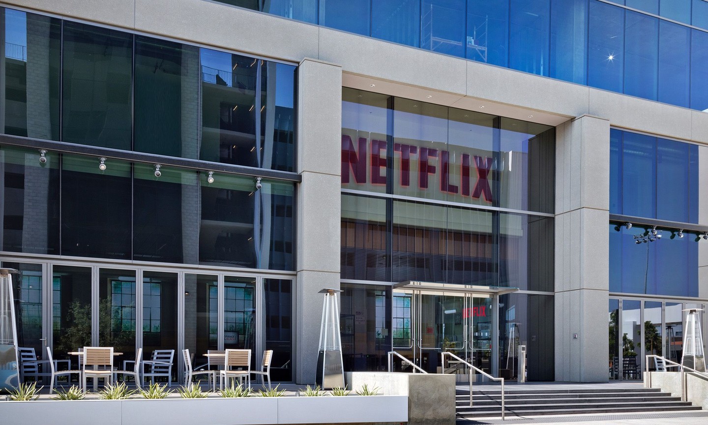 Netflix office entrance in a modern glass-fronted building with outdoor seating