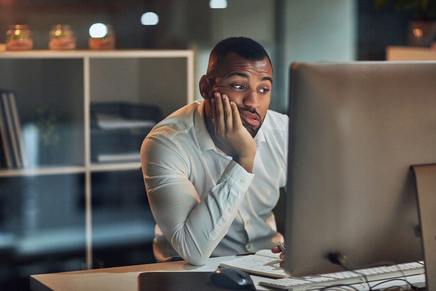 A bored investor is staring at a computer screen.