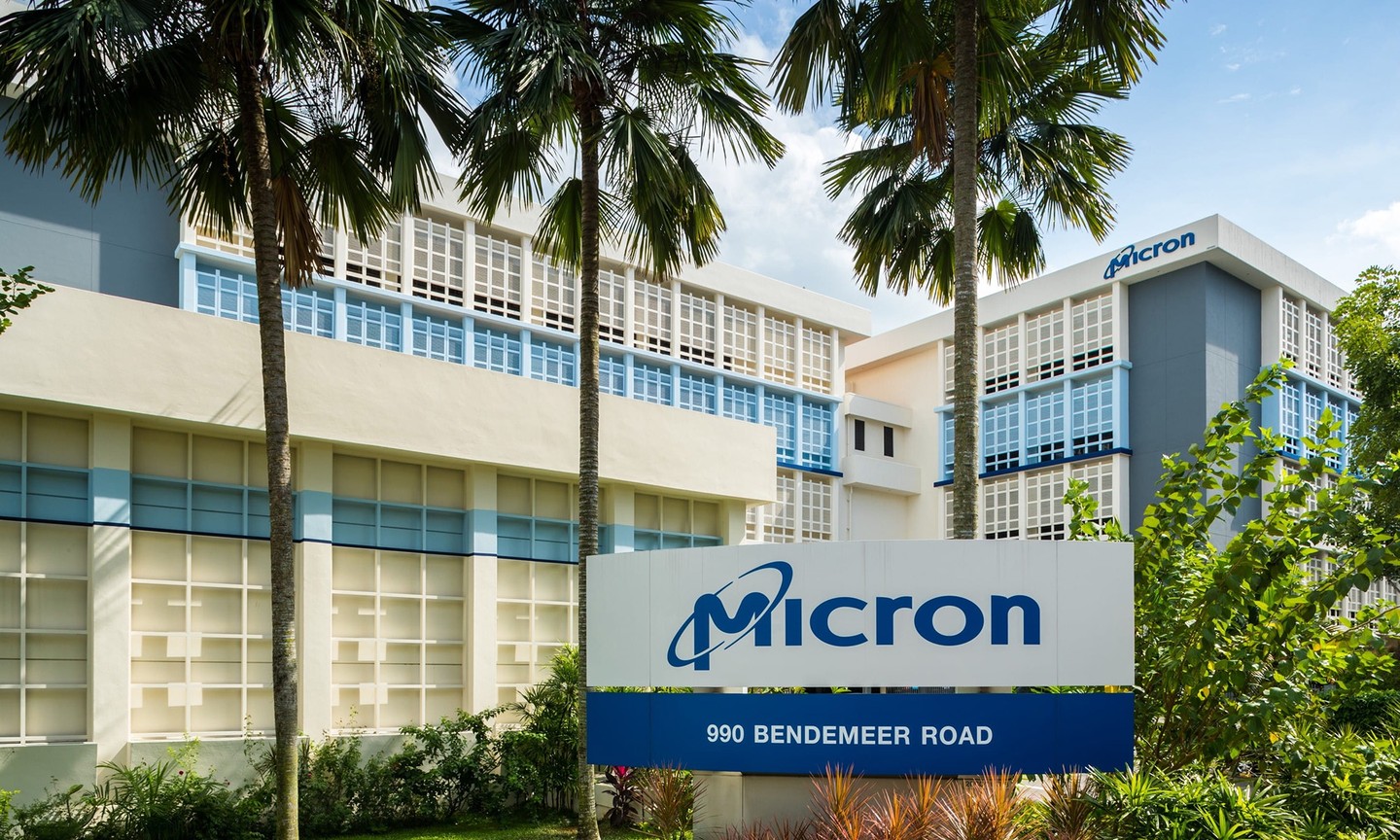 An office building with a sign displaying Micron's logo in front.